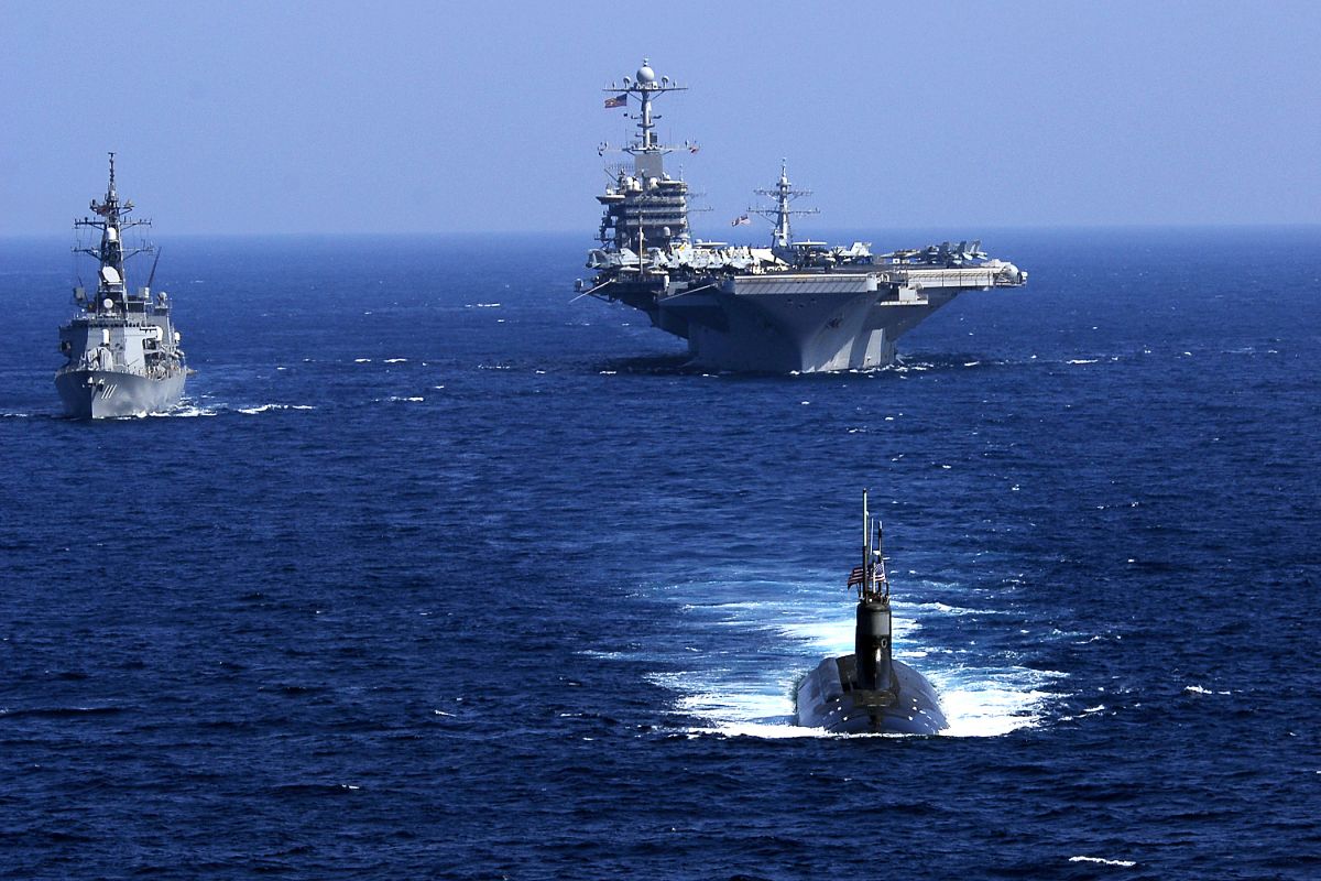 A submarine, destroyer, and aircraft carrier cruising